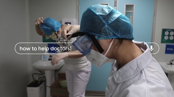 A frame of the video How to Help showing two people wearing medical safety gear, and a search bar on the image with the words "how to help doctors".