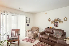 Living room including sliding glass door to patio, white walls and trim, neutral carpet