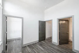 Bedroom with wood-inspired flooring, light walls, and attached bathroom