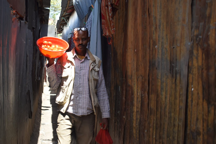 A man hawking tomatoes in between houses at Mukuru Kayaba slum on January 27, 2022