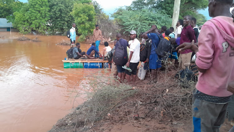 Youths use an improvised "canoe" to cross from Garissa to Madogo following severe damage on the road.