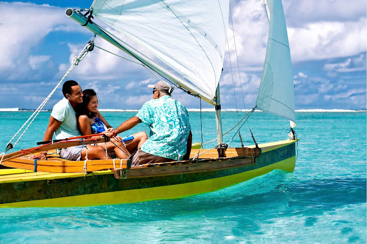 Hop into a sailboat and glide over turquoise waters along a secluded beach in the Cook Islands.