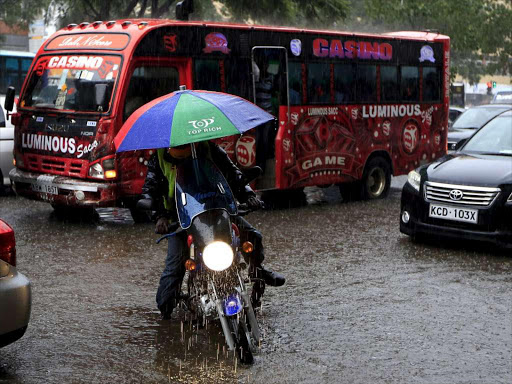 A motorcyclist wades through water during past heavy rains in Kenya's capital Nairobi.