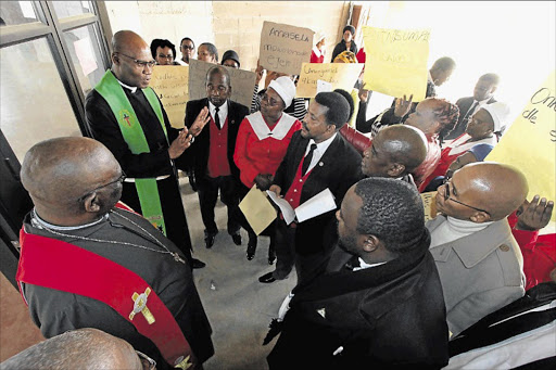 SUPPORTING THEIR MINISTER: A church minister, left, speaks to a group of disgruntled members of the Methodist Church of Southern Africa picketing against the removal of Reverend Gcobani Vika during a church service in Mthatha yesterday Picture: LULAMILE FENI