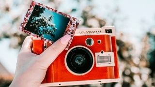 a-man-holding-a-camera-and-photo-in-his-hand