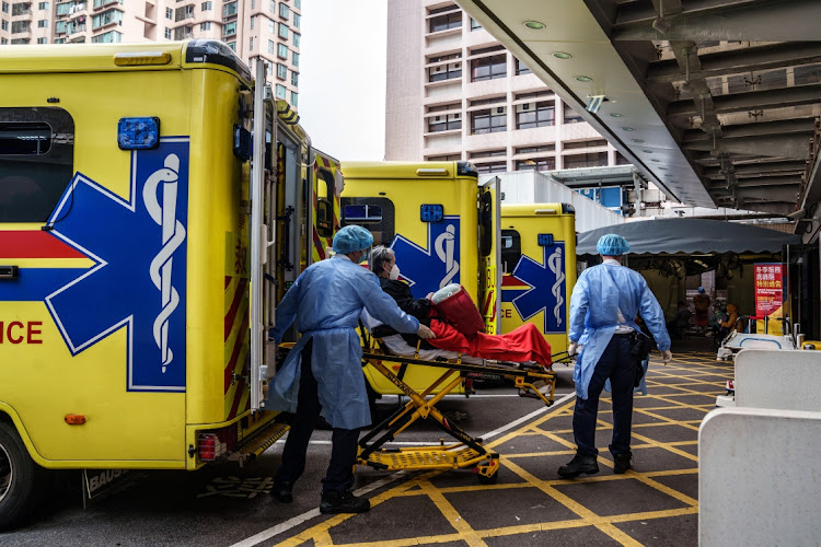 Medics in personal protective equipment transfer a patient from an ambulance at the Queen Elizabeth Hospital in Hong Kong, China, on March 2 2022. Picture: BLOOMBERG/LAM YIK