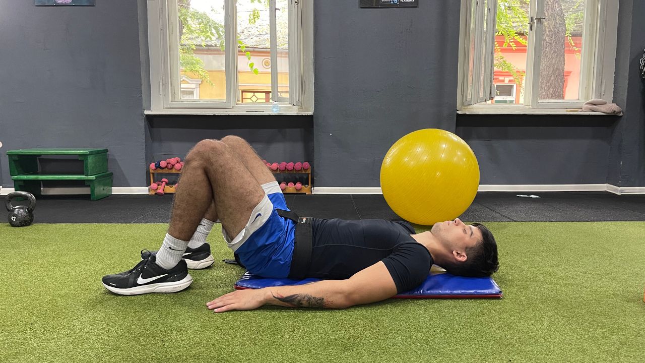 Vanja performs the multifidus strengthening exercise for lower back pain in the commercial gym setup.