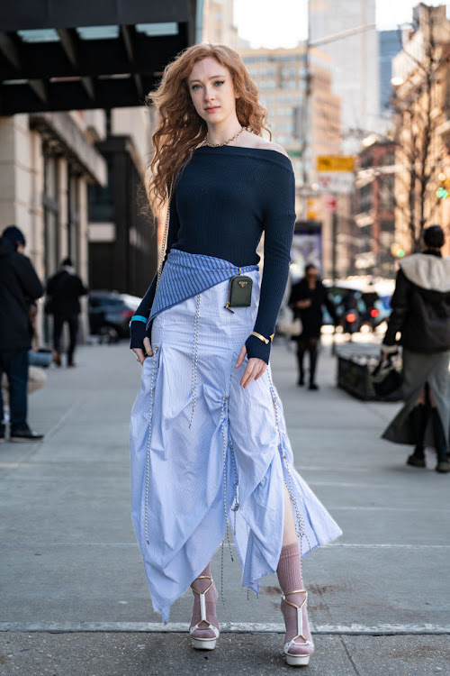 A woman wears a minimal logo design on a Prada cross bag.