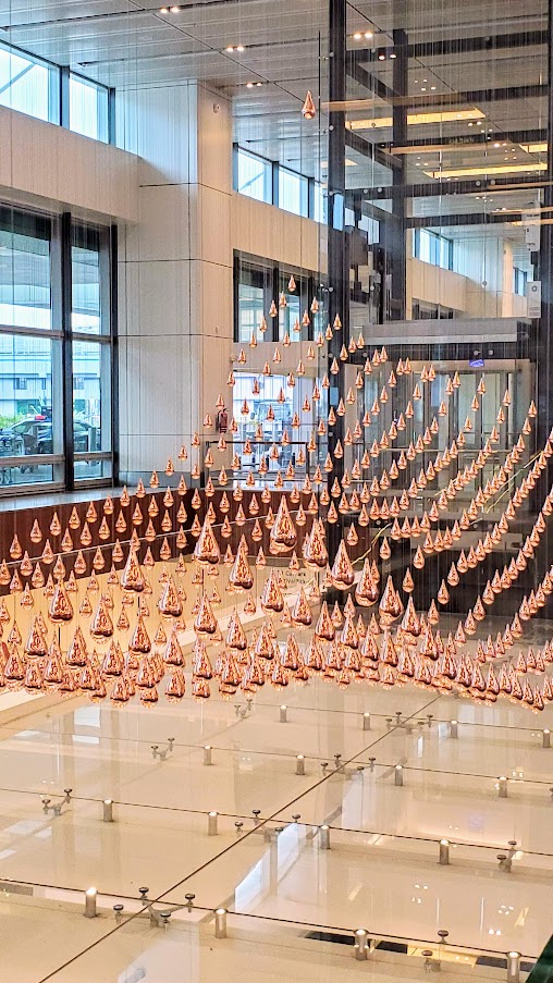 Visiting Changi Airport in Singapore: Kinetic Rain in Terminal 1, a moving sculpture of 1,216 bronze droplets that move up and around to flow into different shapes.