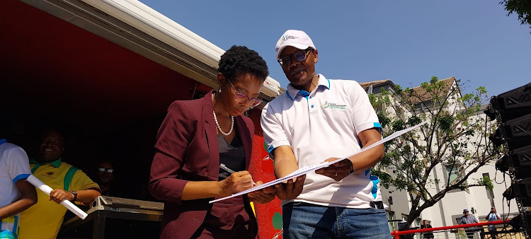 Acting public protector Kholeka Gcaleka, seen with Jacob Zuma Foundation spokesperson Mzwanele Manyi, signs a memorandum of demands presented by political parties and civil society organisations in Pretoria.