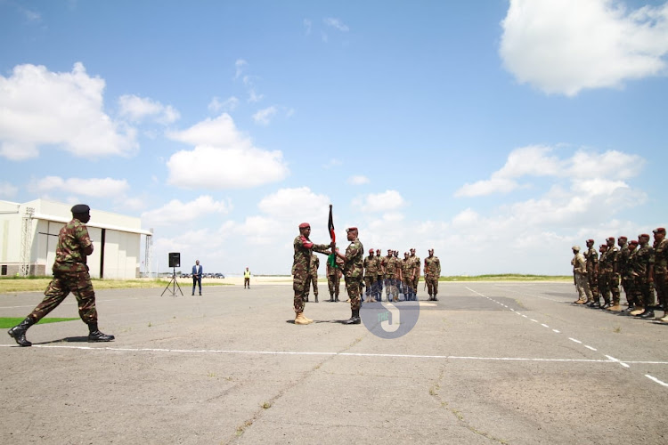 Chief of Defence Forces Francis Ogolla hands over a Kenyan flag to KDF troop from the Democratic Republic of Congo when they arrived at the Embakasi Garrison in Nairobi on December 21, 2023.