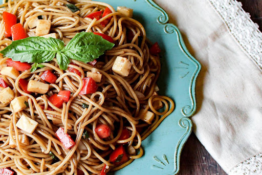 Spaghetti with mozzarella and tomato on a blue plate.