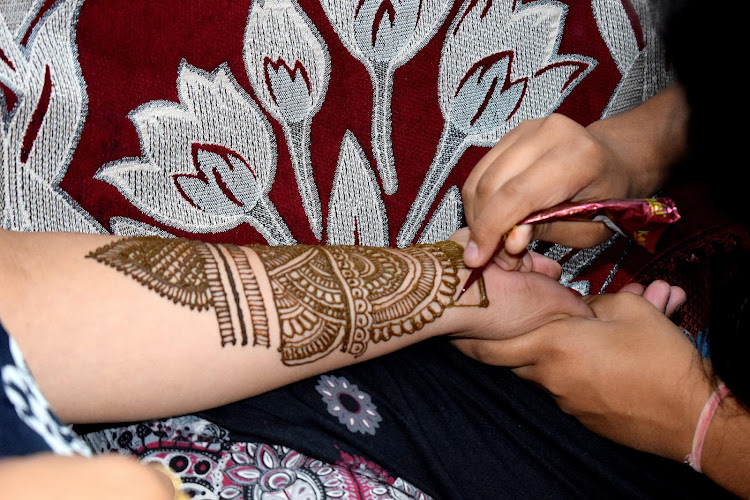 a woman gets henna art on her hand