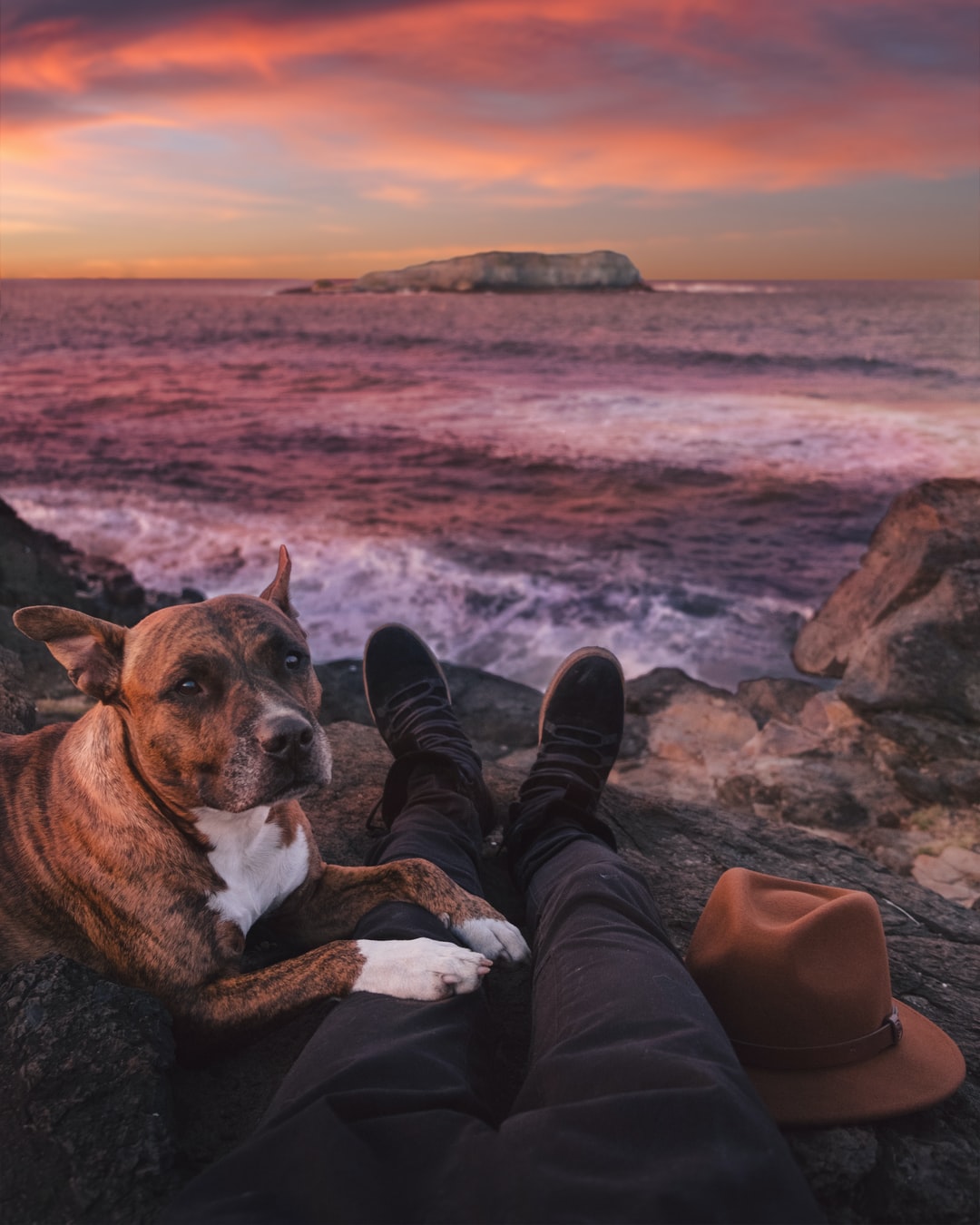 person sitting on rock beside of brindle through sea waves crashing on rock