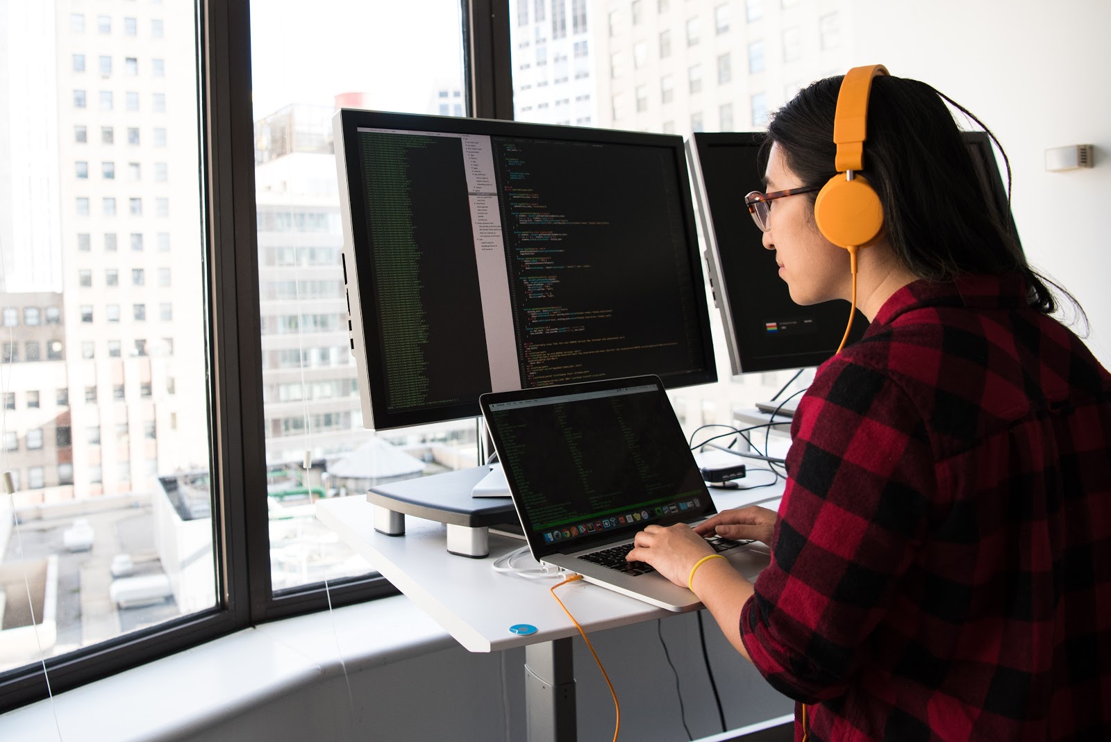 A woman wears headphones and works on a computer