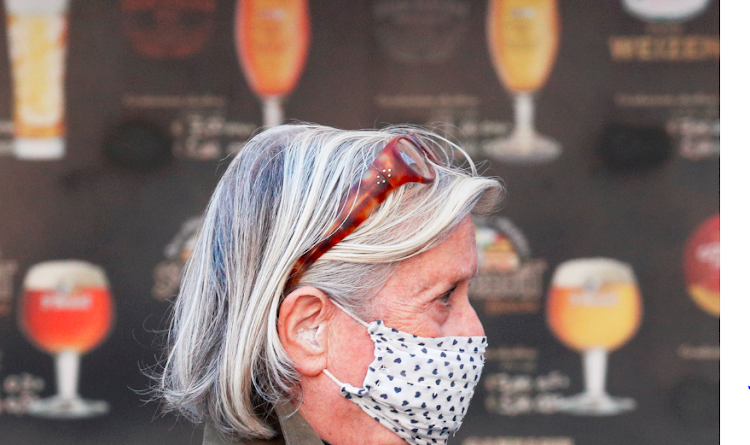 A woman wearing a protective face mask walks past a pub at Campo de' Fiori following the government decision to implement further restrictions in order to help cut down the rate of the coronavirus disease infections in Rome, Italy on October 19 2020.