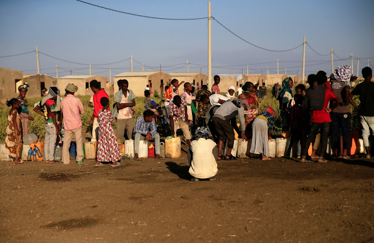 Armed men guard sacks of food delivered to Ethiopian refugees fleeing from the ongoing fighting in Tigray region, at the Fashaga camp, on the Sudan-Ethiopia border.