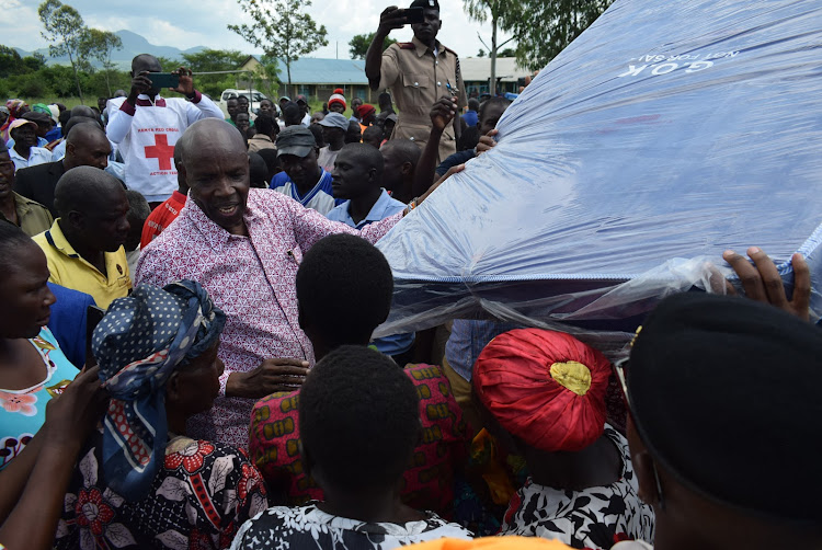 Education CS Ezekiel Machogu gives a mattress to flood displaced person in Nyatoto, Suba South constituency during distribution of relief food on December 11,2023