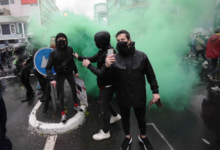 Gender-based violence demonstrators are engulfed in smoke from a police grenade near parliament in Cape Town on August 29 2020.