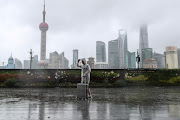 A man with walks in the rain as Typhoon In-fa approaches Shanghai, China on July 25 2021. Tropical storm Talim has strengthened into a typhoon and is set to to make landfall in China later today. File photo. 