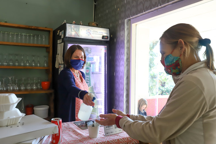 Country Bumpkin owner, Caitlin Mostert sprays hand sanitiser on customer, Antoinette Meise before she collects her order. The restaurant, set in a large garden with outdoor dining, a children’s play area and a wood-fired pizza oven at Floradale in Beacon Bay, closed its doors on Sunday with the loss of 16 jobs.