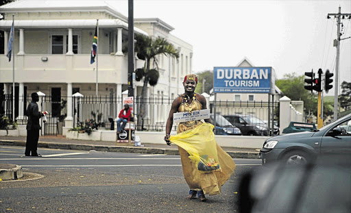 A male street beggar asks for money to collects drivers' rubbish.