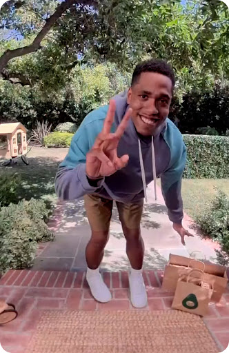 Man seen through Nest doorbell showing peace sign