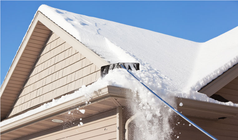 A telescopic snow rake is being used to clear snow off of a roof.