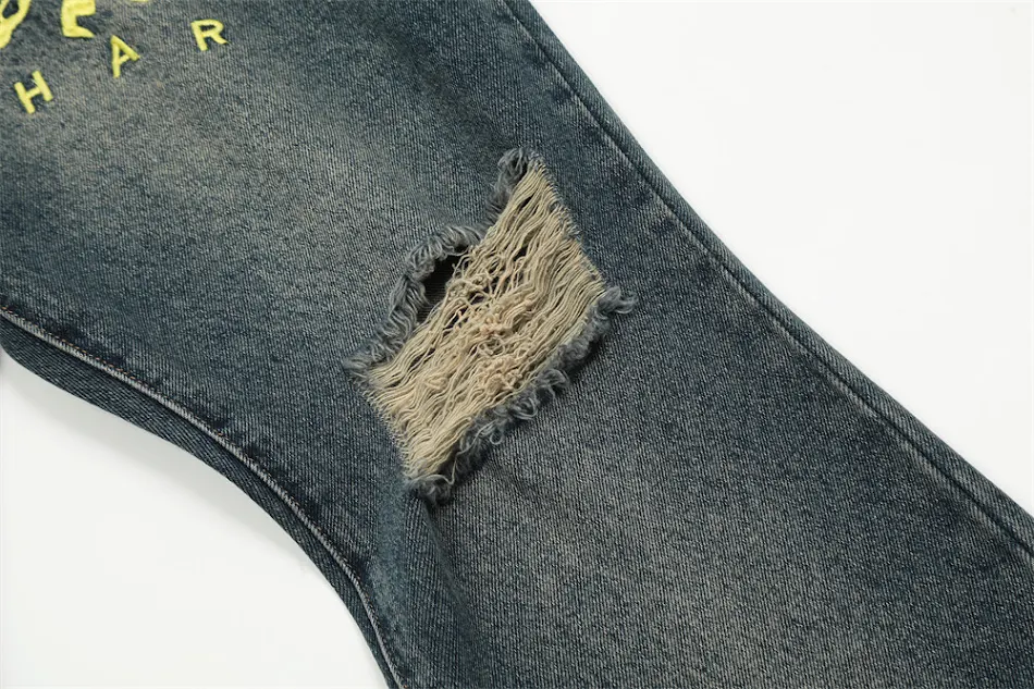 Heren jeans met geborduurde gaten en licht uitlopende pijpen, voor een moderne, casual look die comfort en stijl combineert.
