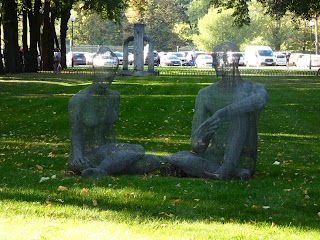 Проволочная скульптура сидящей на земле пары