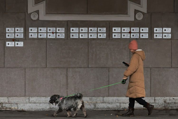 A woman walks with a dog past memorial plaques installed on the wall of an apartment building in remembrance of the victims of Soviet-era political repression in Saint Petersburg, Russia October 28, 2023. REUTERS/ANTON VAGANOV