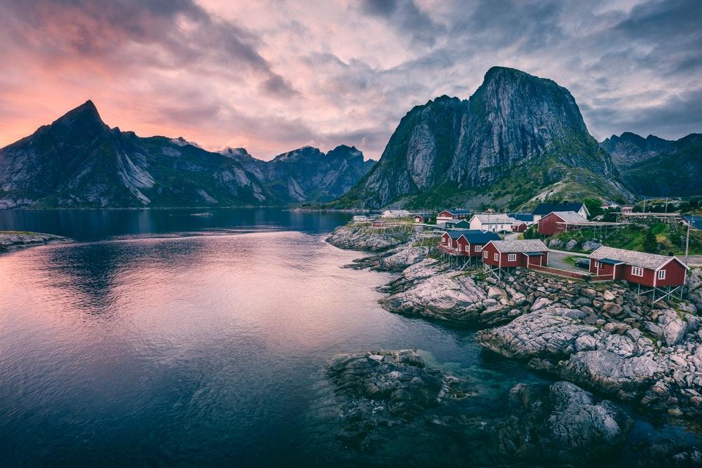 body of water near houses and mountains