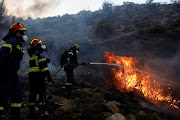 Firefighters and volunteers try to extinguish a wildfire near Vari, south of Athens, Greece June 4, 2022.   