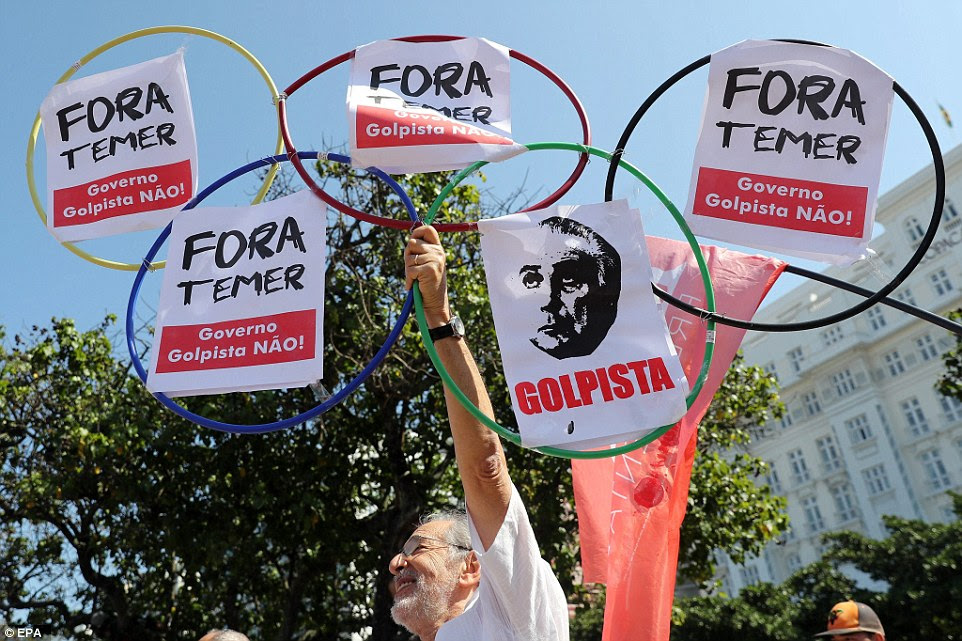 Um manifestante segurava anéis olímpicos com um slogan que se traduz como "Temer para fora! ' - Referindo-se ao presidente interino do Brasil Michel Temer, em São Paulo, Brasil