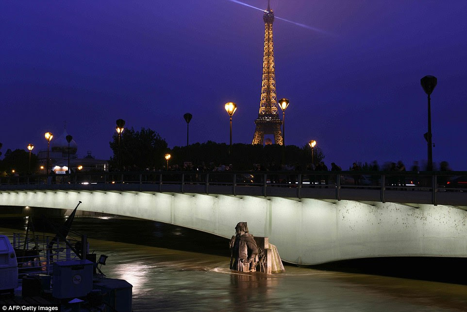This nighttime view of the Eiffel Tower shows how the level of the River Seine is nearing the level of one of Paris' many bridges