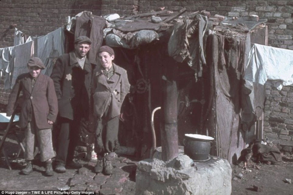 Ghetto boys: In their tattered rags the two boys smile for the camera, but the man in the centre, most probably their father, has a look of distrust etched across his face 