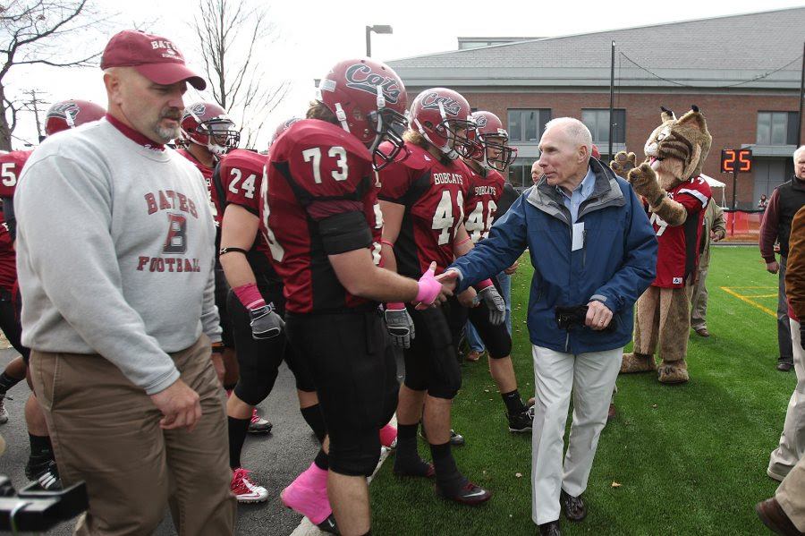 Paul Perry '57, a member of the 1956 Maine State Series champion football team, greets Brendan Murphy '11 as the Bobcat football team heads onto the field for its Homecoming game vs. Colby in 2010. (H. Lincoln Benedict '09)