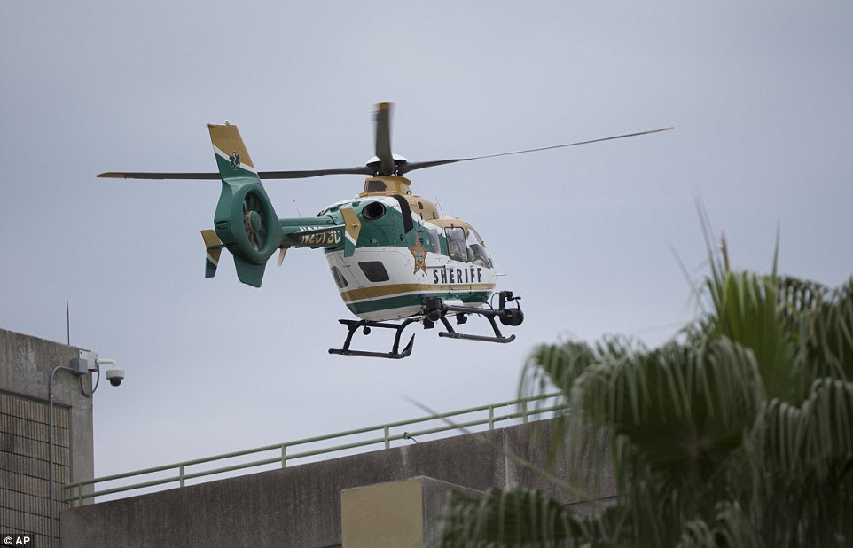 A law enforcement helicopter is seen flying over a garage at the airport after it was put into lockdown