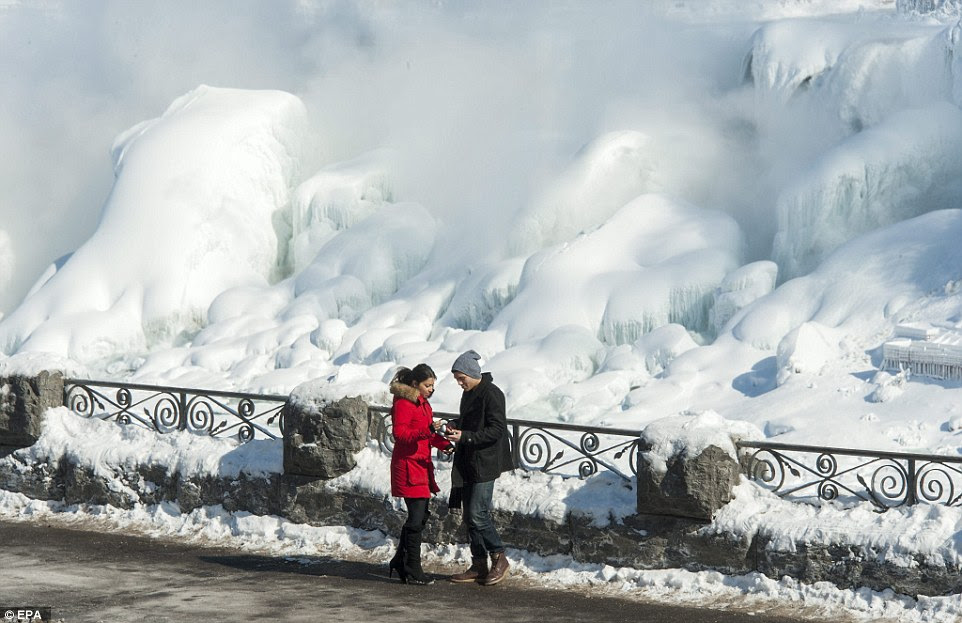 Tourists: 'I come here every winter but this is the most magnificent,' said Heather Ferrara of nearby Tonawanda, who visited the Falls with her husband amid minus seven temperatures. Above, tourists take pictures of The American Falls (rear) from the Niagara Falls on Friday