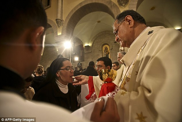 A nun takes communion from Latin Patriarch of Jerusalem Fuad Twal during the midnight mass ceremony which marks the beginning of Christmas Day