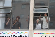 Residents watch as protesting students make their way through Braamfontein, Johannesburg, on March 3 2023 during the third day of protest action.