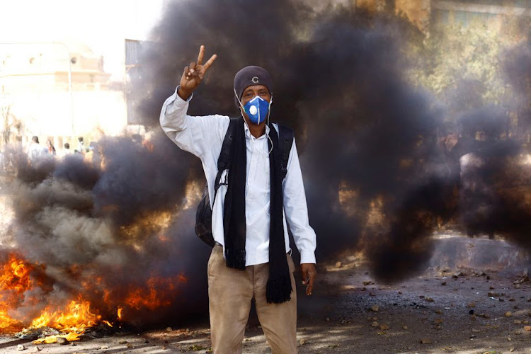 Sudanese protester stands in front of a blazing fire during a demonstration against the military coup, on International Women's Day in Khartoum, Sudan March 8, 2022.