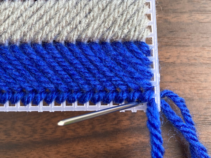 making a whip stitch on plastic canvas using blue colored yarn