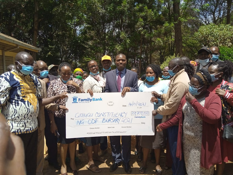 Gichugu MP (In suit) and parents hold a Sh 37.7 million dummy cheque for bursary beneficiaries.