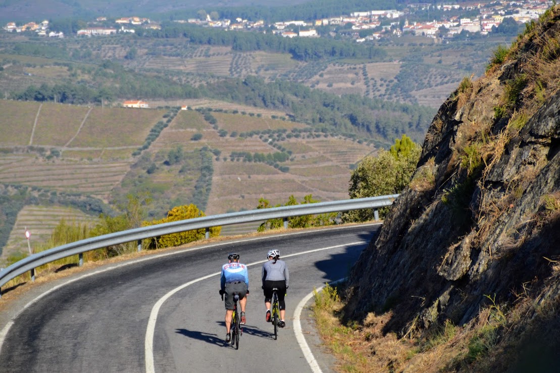 Sporty couple cycling on road bikes along the hills in the Douro valley