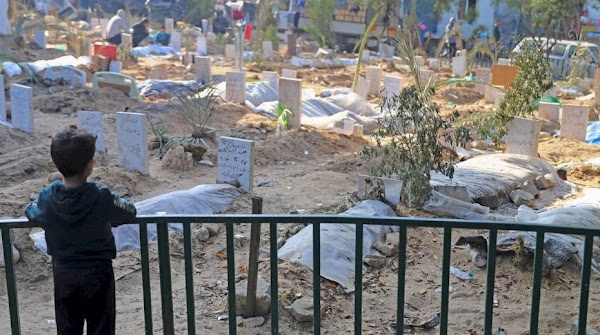 Junge sieht von einem Balkon auf einen Friedhof mit frischen Gräbern.