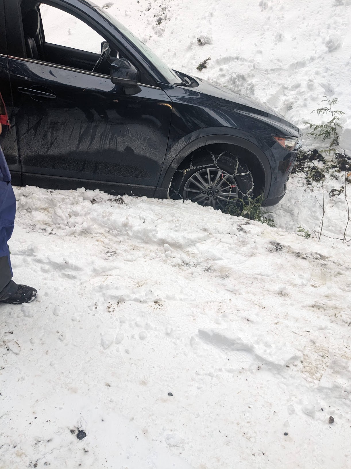 Car with its front half in a snowy ditch