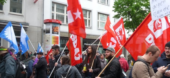 Ostermarschierende mit roten und blauen Fahnen.