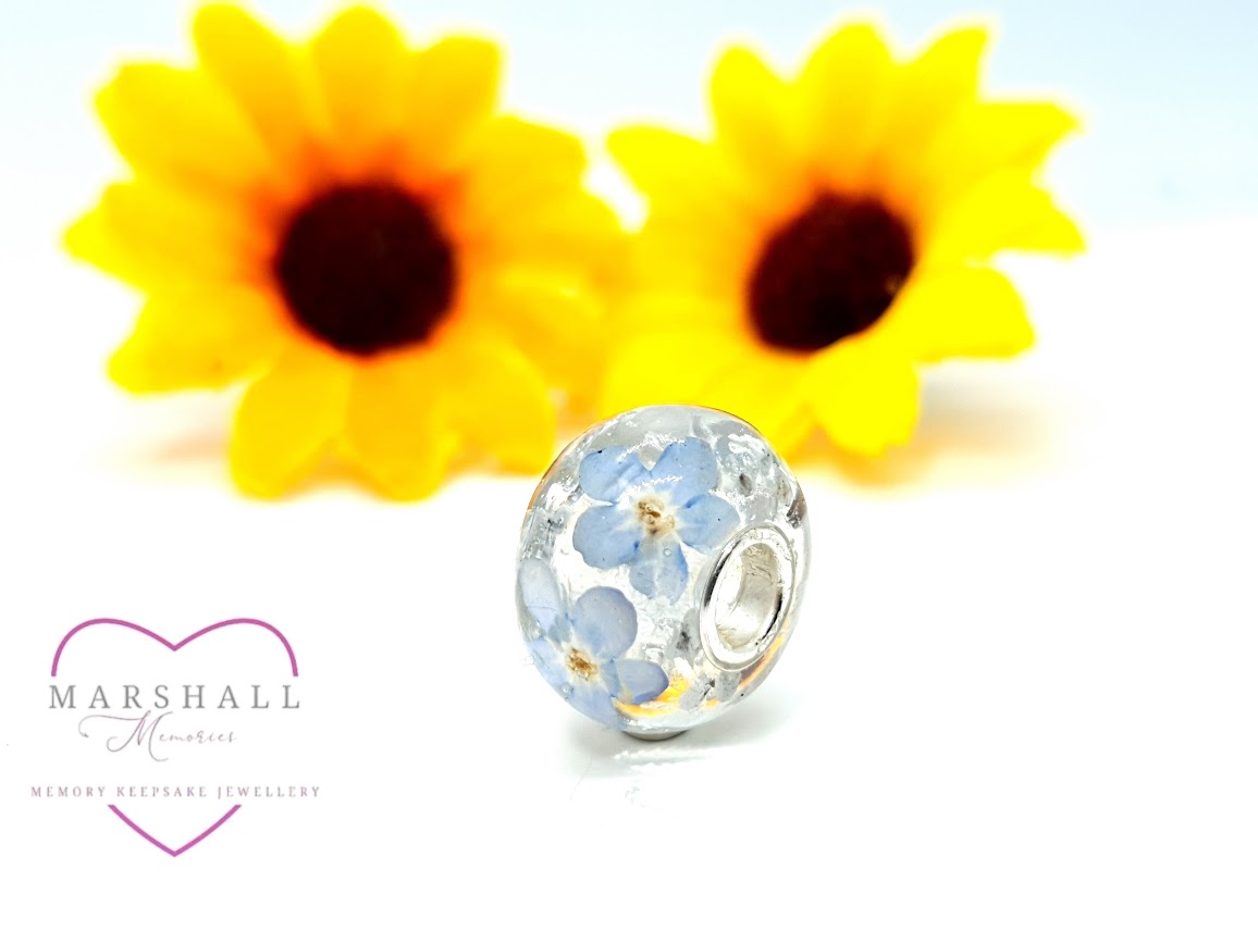 A memory keepsake charm bead from Marshall Memories with sunflowers in the background as decorations.