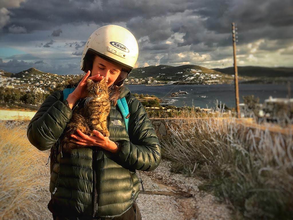 A girl holding a small stray kitten on Syros Island in Greece